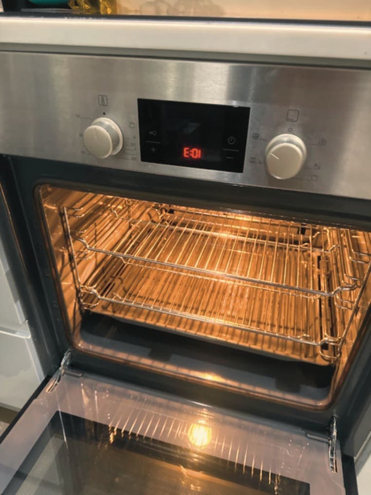 Stainless steel single oven after professional cleaning, racks and glass door gleaming